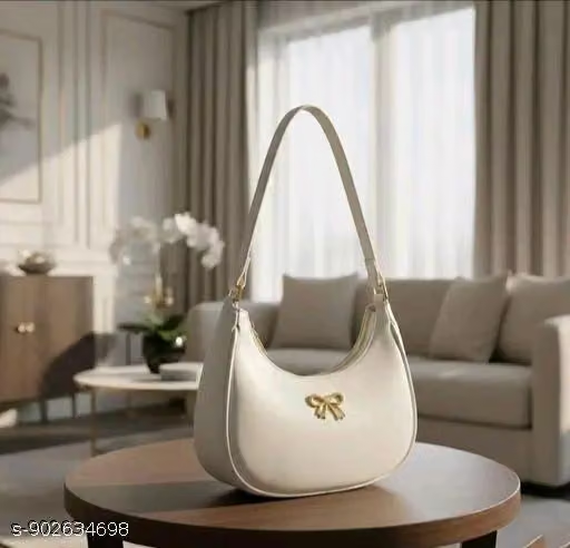 Cream half-moon handbag with golden bow detail on table in living room